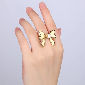 Macro shot of 18k gold plated bow ring with central zircon on a finger