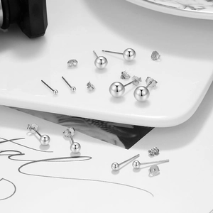 Macro detail of various S925 sterling silver ball stud earrings in multiple sizes on a plate