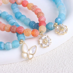 Macro shot of colorful agate beaded bracelets with gold butterfly and flower charms