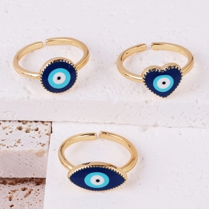 Detailed view of three gold evil eye rings with blue enamel inlay on a marble stone