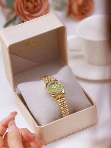 Detail view of a gold-tone women's watch with green dial and crystal bezel in a luxury box