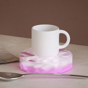 Nahaufnahme der mattweißen Keramiktasse auf rosa Marmor-Untersetzer mit feinem Geschirr