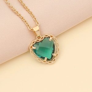 Detail view of a gold heart pendant with green gemstone on a classic O-chain necklace