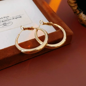 Macro detail of high-polish gold round hoop earrings on a brown velvet display