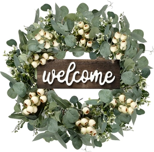 Close-up of faux eucalyptus wreath with white berries and a wooden welcome sign