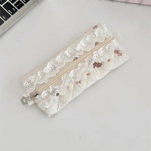 Detailed shot of cream quilted pencil case with lace trim and silver flower zipper