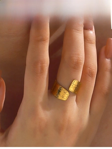 Macro detail of golden wide band ring with irregular hammered texture on a model hand