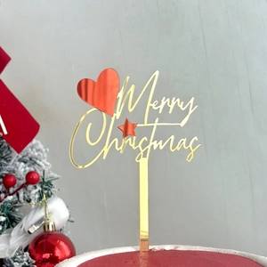 Macro detail of Merry Christmas acrylic cake topper with golden mirror finish and red heart