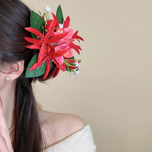 Detail of elegant red fabric flower hair clip with green leaves worn on the side
