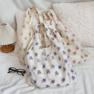 Three canvas tote bags with embroidered floral patterns in purple, pink, and green colors