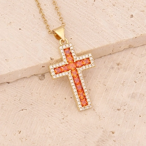 Detailed shot of golden cross necklace with orange and white cubic zirconia crystals