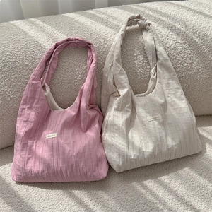 Detail of pink and beige pleated fabric tote bags with a soft textured aesthetic