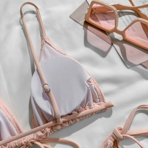 Detail of pink textured bikini top with adjustable silver metal buckles and halter straps