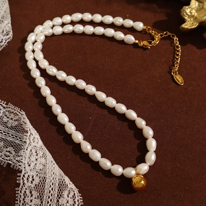Elegant freshwater pearl necklace with gold sphere pendant on premium brown velvet fabric