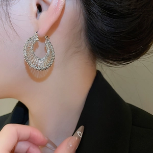 Macro detail of silver woven metal earrings with industrial hollow texture on model