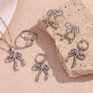 Detailed view of silver bow jewelry set with white zircons on a beige mineral stone