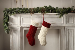 Close-up of red and cream knitted Christmas stockings with cable patterns on a white mantel