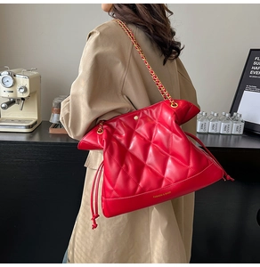 Detailed view of red quilted leather bucket bag with gold chain strap on model