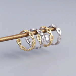 Close-up of gold and silver chain link rings displayed on a metal rod with soft lighting