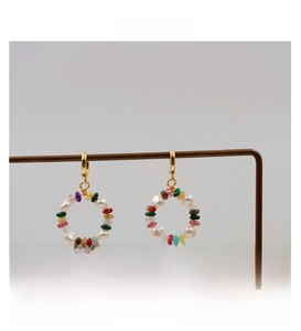 Macro shot of colorful stone and white pearl circle earrings on a vintage metal display
