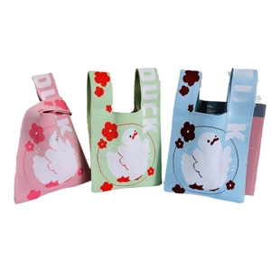 Three colorful knitted wrist bags featuring cute cartoon ducks and floral patterns