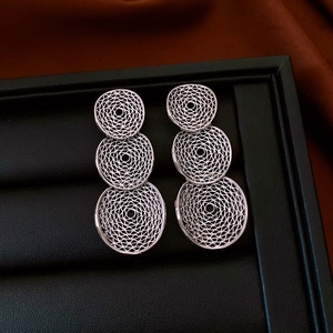 Detail of silver drop earrings featuring triple hollow mesh circles with spiral texture