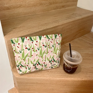 Close-up of tulip floral canvas makeup bag on stairs with a coffee cup accessory