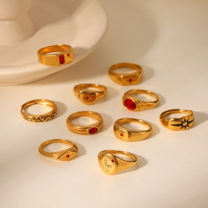 Detail of vintage gold rings set featuring red gemstones and star motifs on white ceramic