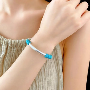 Gros plan d'un bracelet ethnique en perles de turquoise et tubes argentés au poignet