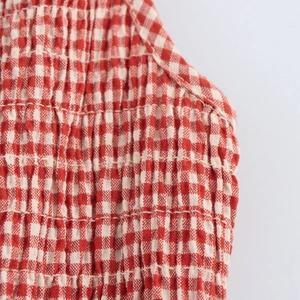 Plaid smocked sleeveless dress in red and white fabric with a waist-slimming long silhouette