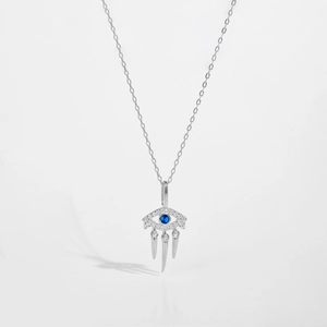 Macro shot of silver evil eye necklace with blue gemstone and hanging tapered charms