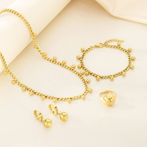 Detailed view of a four-piece golden jewelry set featuring chains and spherical pendants