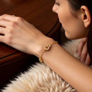 Détail d'un bracelet plaqué or 24 carats avec un cœur évidé et un pendentif gourde serti