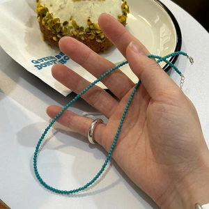 Minimalist turquoise beaded necklace and polished 925 silver ring shown in a lifestyle setting