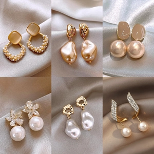 Elegantes Set aus sechs goldenen Blumen- und Perlenohrringen auf seidigem Stoff