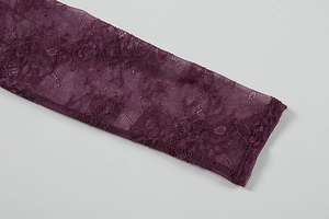 Macro detail of dark purple floral lace fabric and delicate stitching on long sleeves