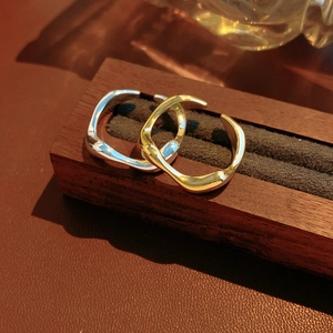 Close-up of 18k gold and silver plated irregular wavy open rings on velvet stand