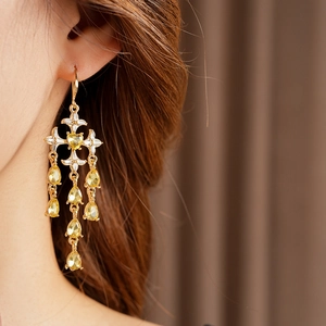 Detail of vintage gold tassel earring with heart gemstone and star cross design