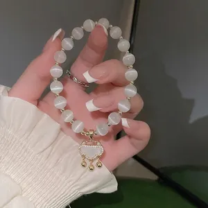 Opalperlen-Armband mit goldenem Schlossanhänger und kleinen Kristallen am Handgelenk