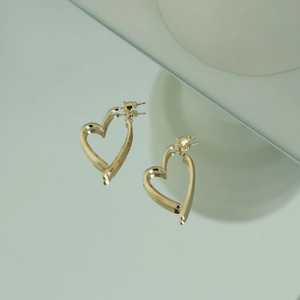Detailed top view of gold heart-shaped stud earrings featuring a reflective mirror finish