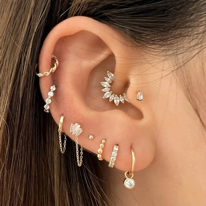 Close-up of golden star and moon charms with zircon inlays worn on ear piercings