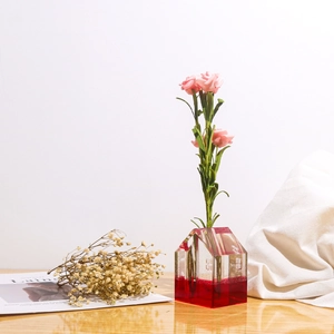 Vaso in resina trasparente a forma di casa con base rossa e rose finte rosa