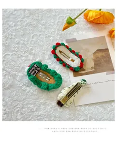 Close-up of handmade knitted Christmas tree hair clips with vintage lace background