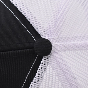Top detail of black and white trucker hat featuring mesh fabric and reinforced stitching