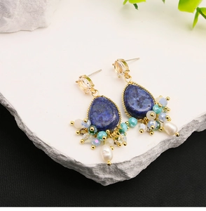 Detail showing blue teardrop stones and freshwater pearls on bohemian gold earrings