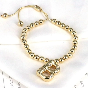 Detail of adjustable gold beaded bracelet featuring a sparkling zircon initial B pendant