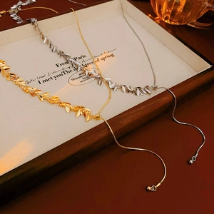 Detailed view of gold and silver sequin fringe necklaces on a vintage wooden tray