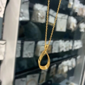 Macro detail of golden teardrop pendant with spiral texture on elegant O-chain necklace