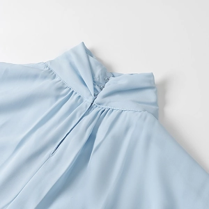 Close-up of light blue chiffon top with pleated high neck and side button detail