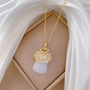 Macro detail of gold-plated safety lock pendant with white faux jade and pavé crystals